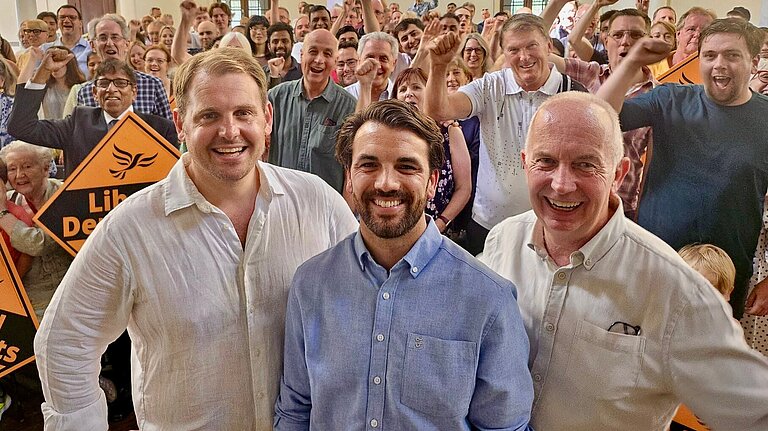 Luke Taylor MP, Bobby Dean MP and Cllr Barry Lewis, with a large crowd of Lib Dems campaigners behind them